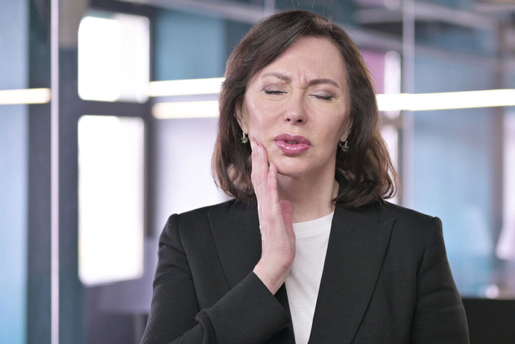 Geschäftsfrau im Büro mit Zahnschmerzen